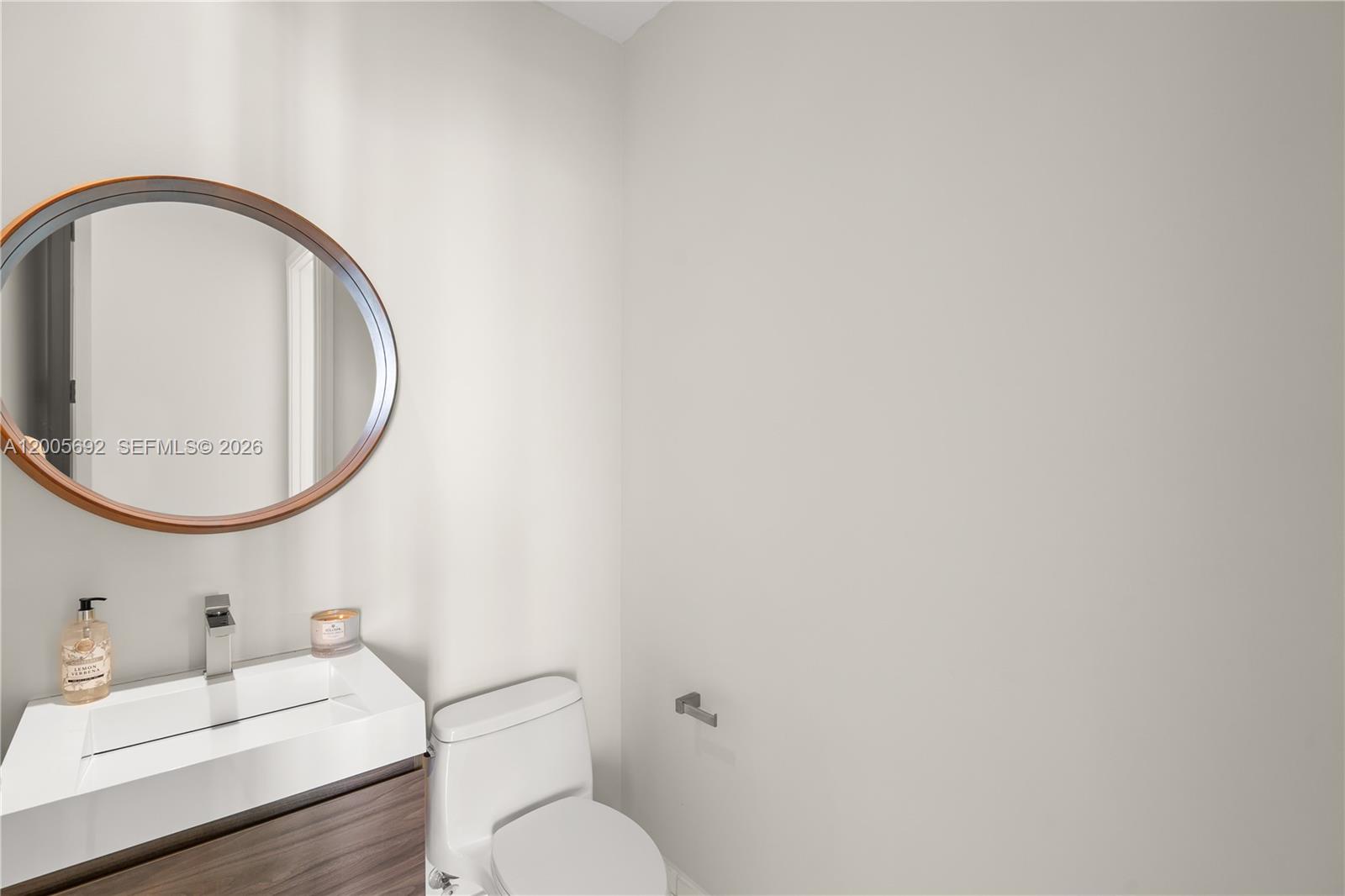 900 Brickell Key Boulevard, Unit 3002 Miami, FL 33131 - Photo 37 of 47 a bathroom with a toilet a sink and a mirror