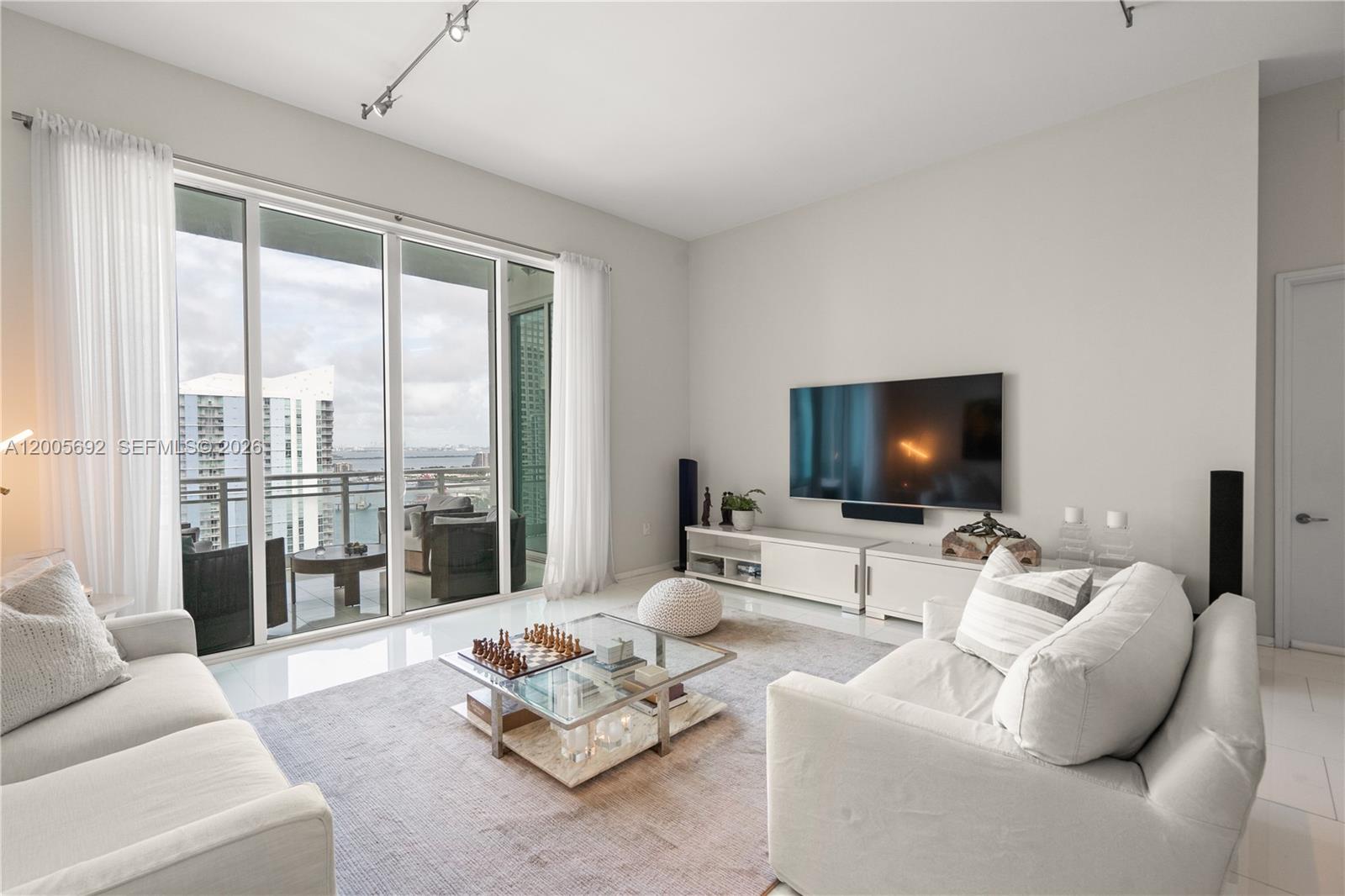 900 Brickell Key Boulevard, Unit 3002 Miami, FL 33131 - Photo 6 of 47 a living room with furniture a flat screen tv and a large window