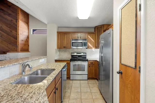 a kitchen with granite countertop a sink stove and refrigerator