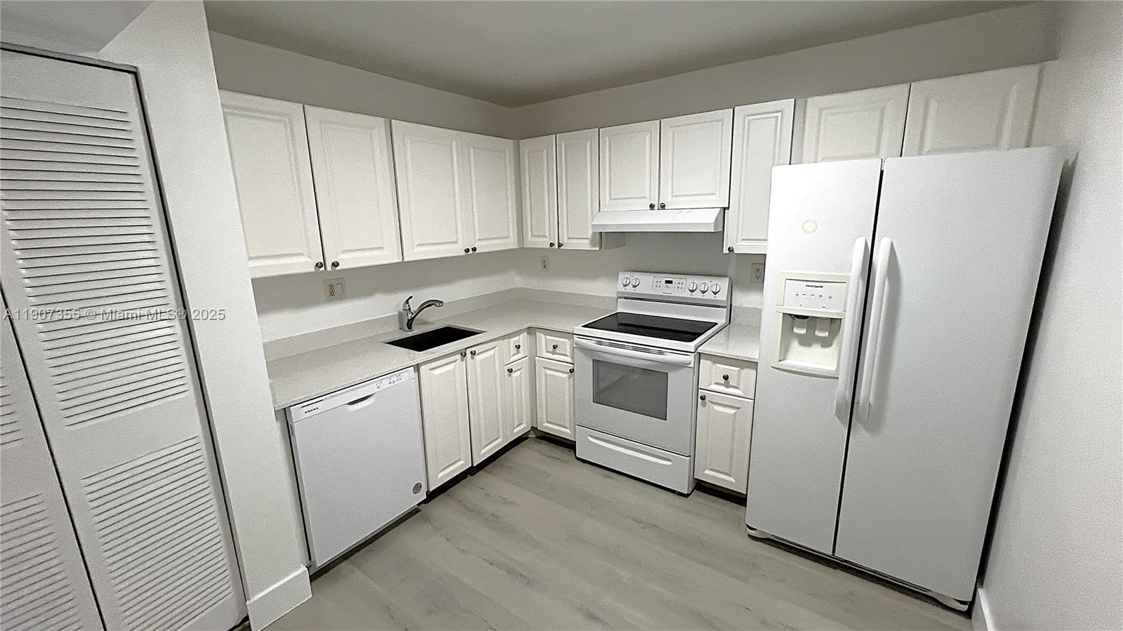 711 North Pine Island Road, Unit 415 Plantation, FL 33324 - Photo 5 of 19 a kitchen with white cabinets and white stainless steel appliances