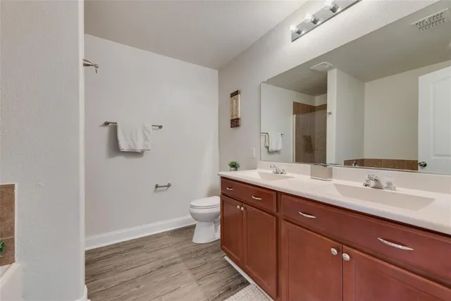 a spacious bathroom with a double vanity sink toilet and mirror