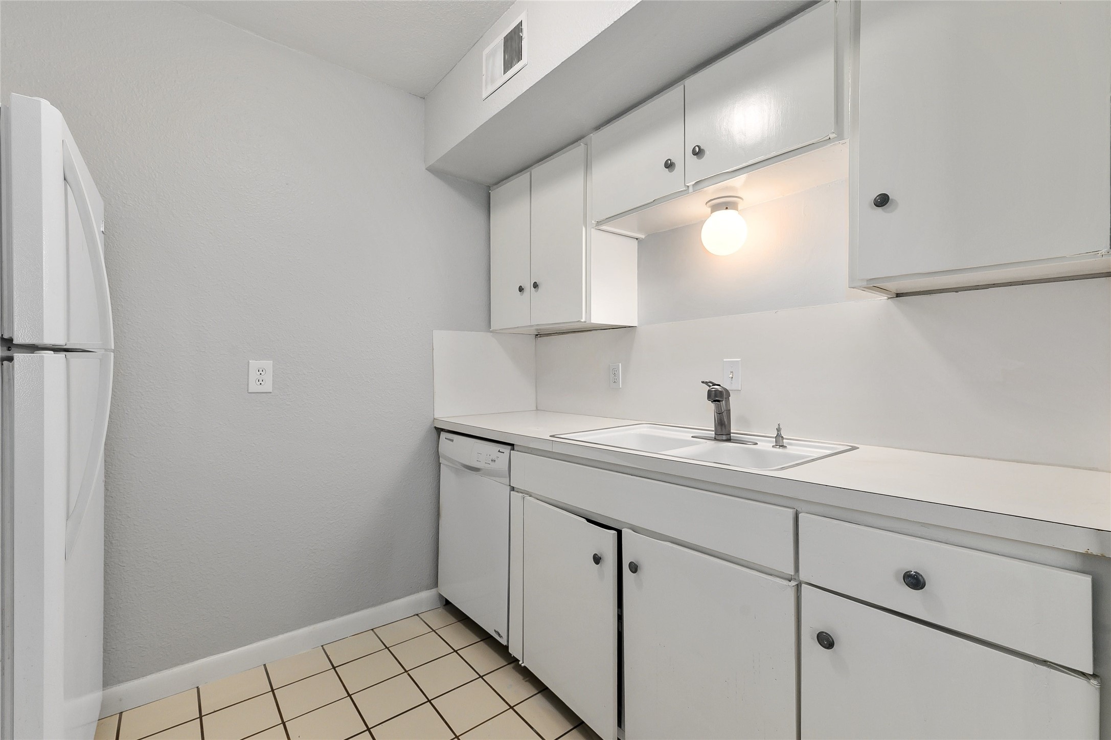 2408 Longview Street, Unit 113 Austin, TX 78705 - Photo 10 of 23 Kitchen with light countertops, white cabinetry, white appliances, and light tile patterned floors