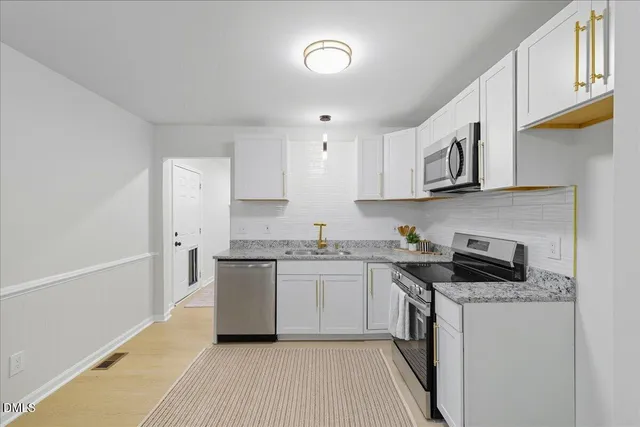 a kitchen with stainless steel appliances granite countertop a sink stove refrigerator and cabinets