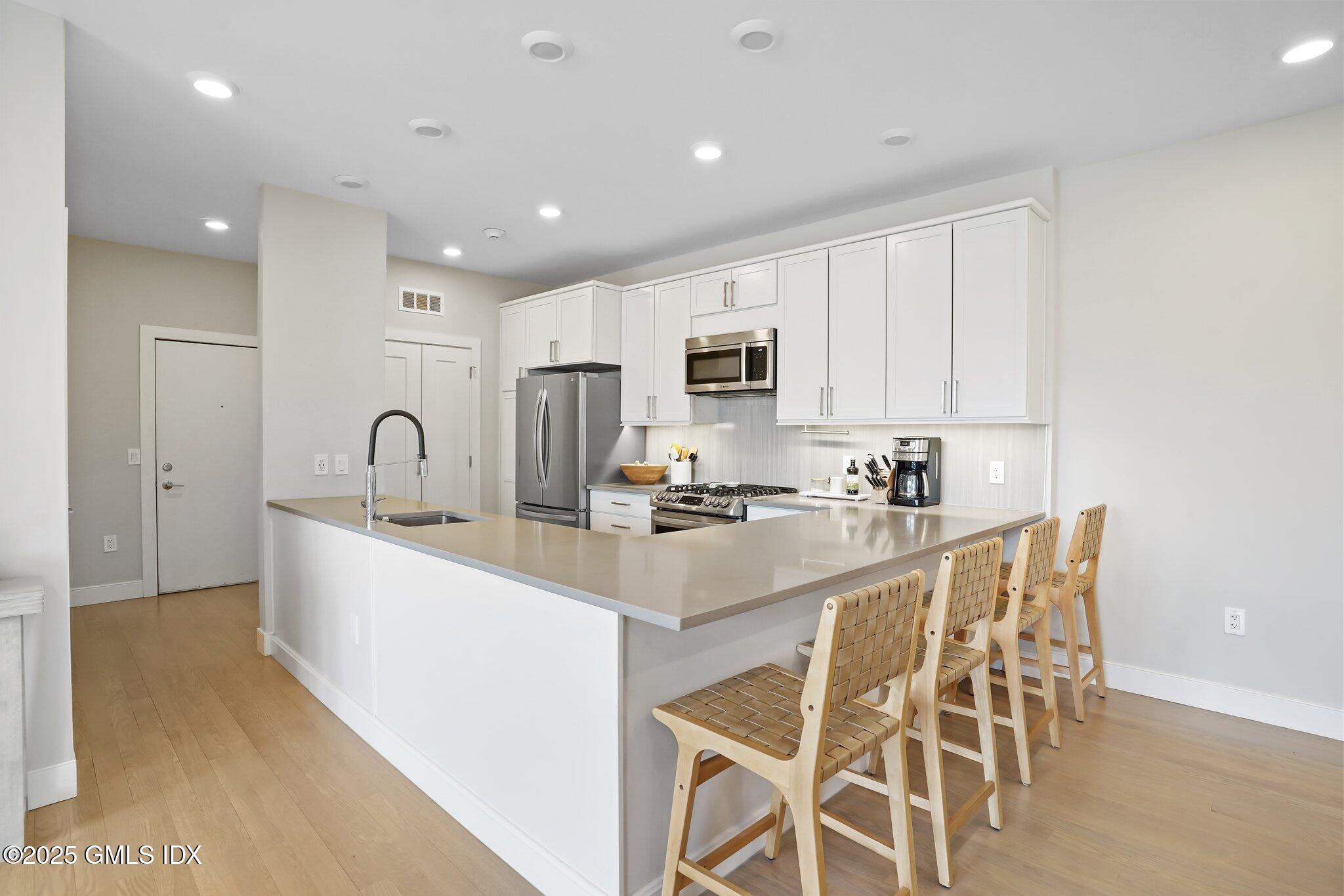 56 Old Field Point Road, Unit 2 Greenwich, CT 06830 - Photo 2 of 20 a large white kitchen with sink a stove a microwave and cabinets