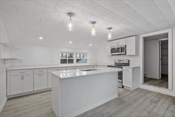 a kitchen with kitchen island white cabinets and refrigerator