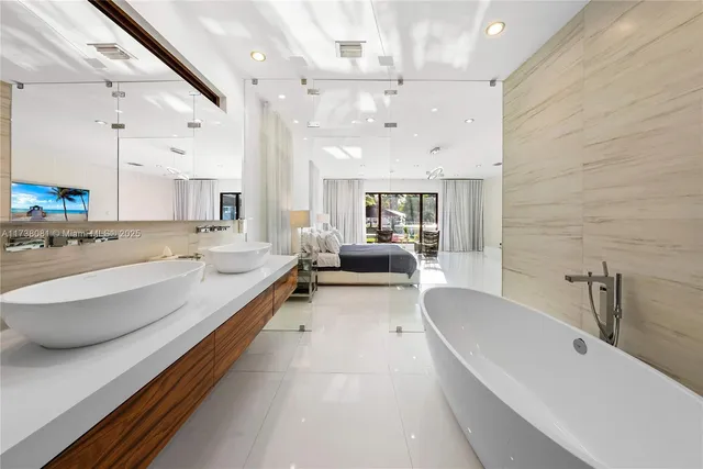a large white bathroom with a large tub double vanity sink and a large mirror