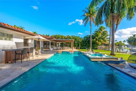 a view of swimming pool with lawn chairs and large trees