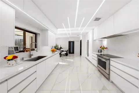 a large white kitchen with stainless steel appliances granite countertop a lot of counter space and a sink
