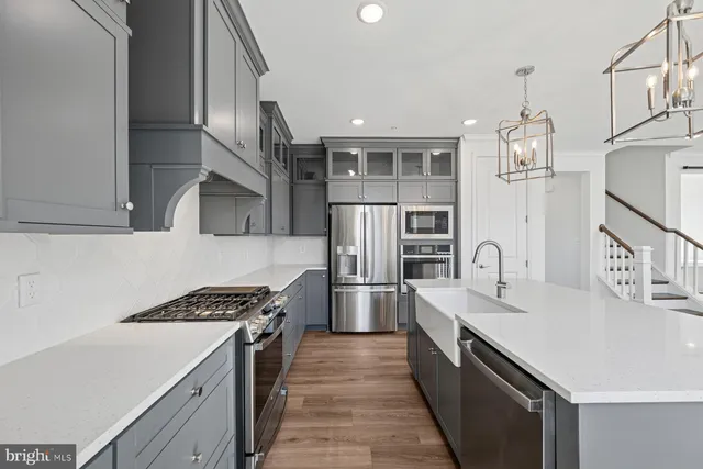 a kitchen with kitchen island a stove a refrigerator and a sink with wooden floor