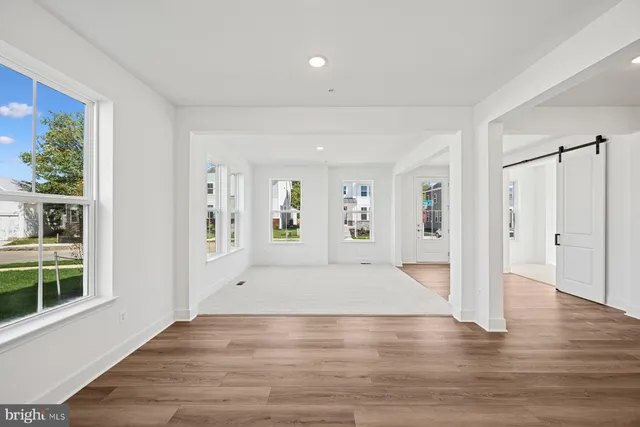 a view of an empty room with window and wooden floor