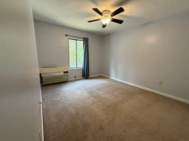 an empty room with windows and fan