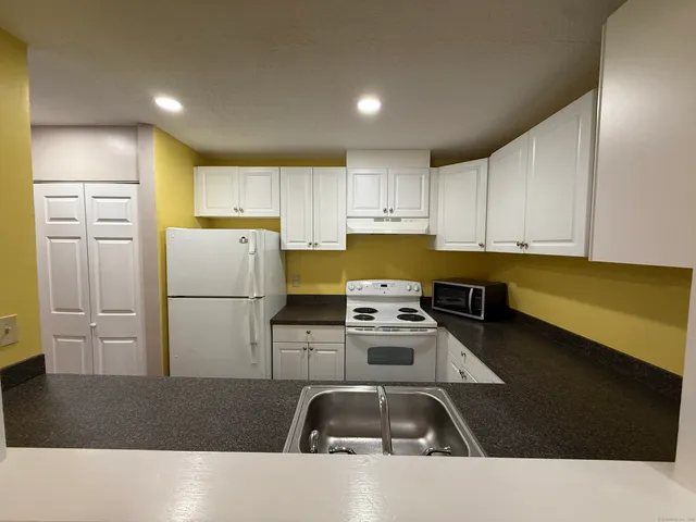 a kitchen with stainless steel appliances a refrigerator a sink a stove and white cabinets