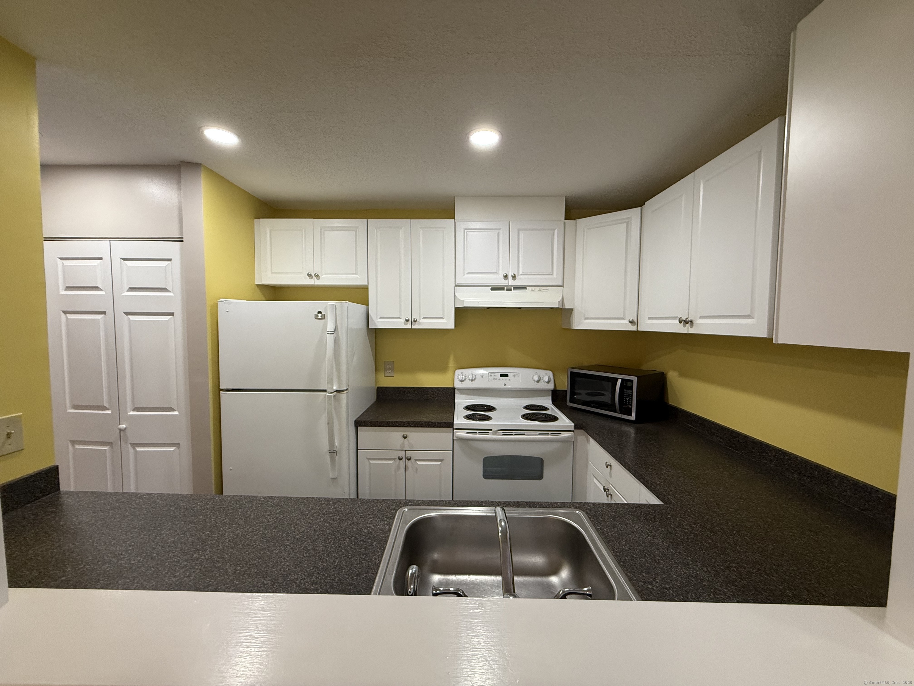 175 Mill Pond Road, Unit 215 Hamden, CT 06514 - Photo 4 of 19 a kitchen with stainless steel appliances a refrigerator a sink a stove and white cabinets