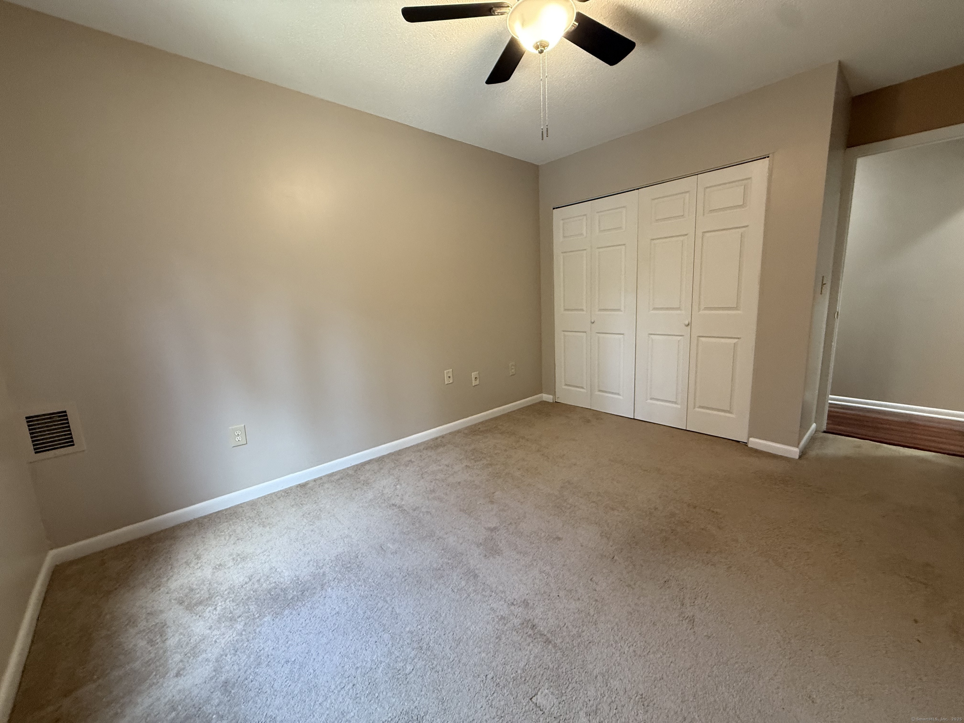 175 Mill Pond Road, Unit 215 Hamden, CT 06514 - Photo 9 of 19 an empty room with a ceiling fan and carpet