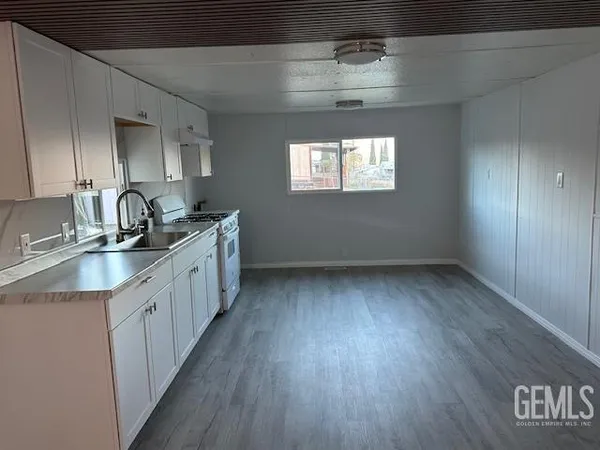 a kitchen with granite countertop a sink stove and cabinets