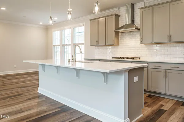 a kitchen with stainless steel appliances granite countertop a sink a stove and white cabinets with wooden floor