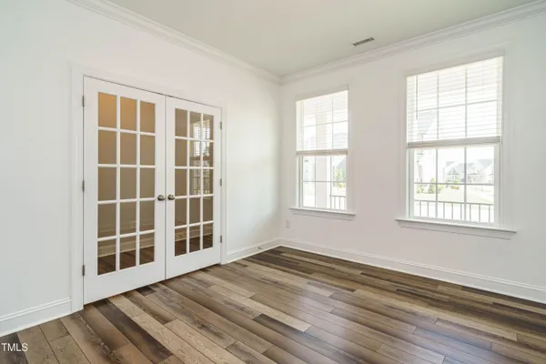 an empty room with wooden floor and windows