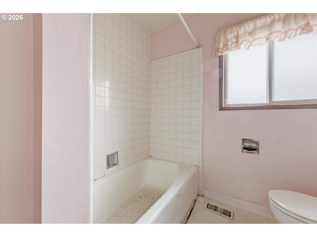 12333 Southeast Madison Street Portland, OR 97233 - Photo 16 of 28 a bathroom with a window a toilet and a bathtub