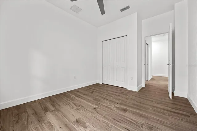 a view of an empty room with wooden floor and a bathroom