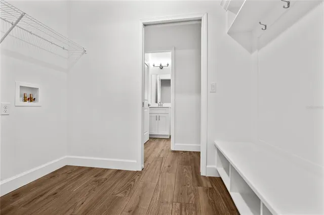 a view of a hallway with wooden floor and a refrigerator