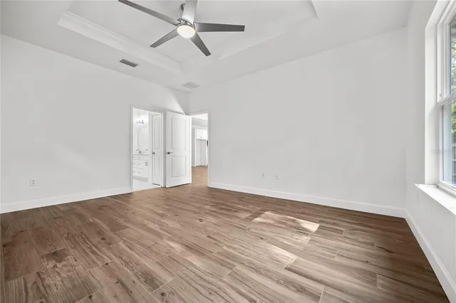 a view of empty room with wooden floor and fan