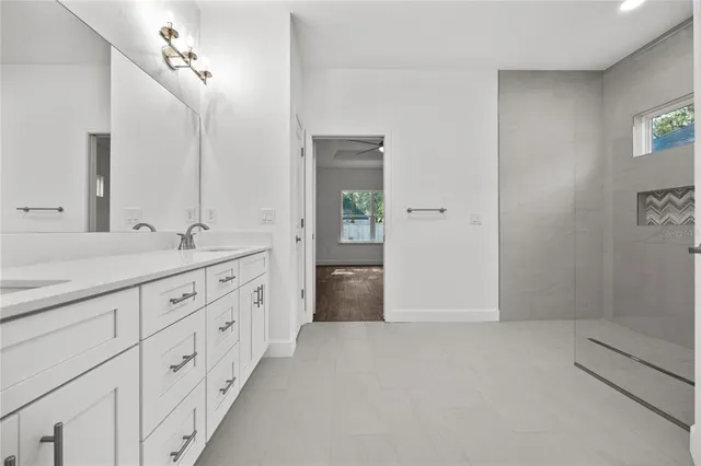 a spacious bathroom with a double vanity sink a large mirror a shower and vanity