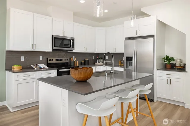 a kitchen with stainless steel appliances granite countertop a sink a stove a refrigerator cabinets and chairs