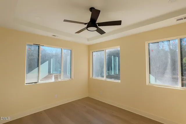 a view of empty room with wooden floor and fan