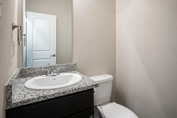 a bathroom with a granite countertop toilet sink and mirror