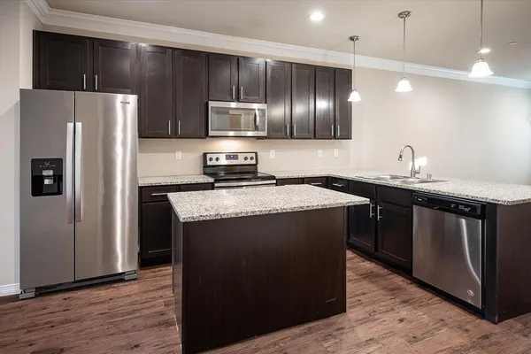 a kitchen with kitchen island granite countertop stainless steel appliances a refrigerator and a sink