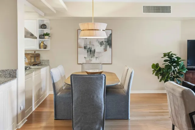 a kitchen with a refrigerator a stove a sink dishwasher a dining table and chairs with wooden floor