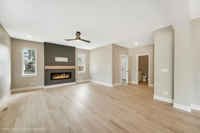 a view of an empty room with wooden floor fireplace and a window