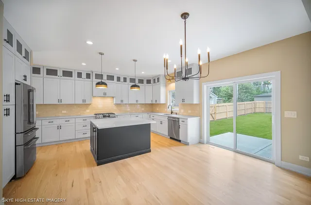 a kitchen with kitchen island a counter top a stove a sink a refrigerator and a view of living room