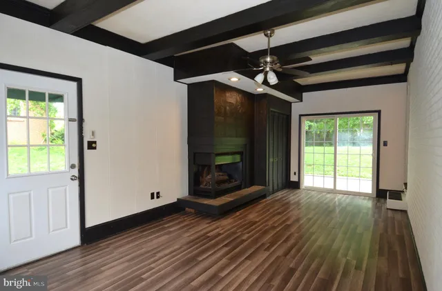 a view of a room with wooden floor a ceiling fan and window