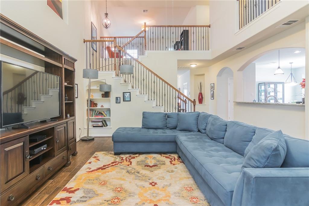 252 Pond View Pass Buda, TX 78610 - Photo 12 of 37 Living area featuring stairs, wood finished floors, a towering ceiling, and a chandelier