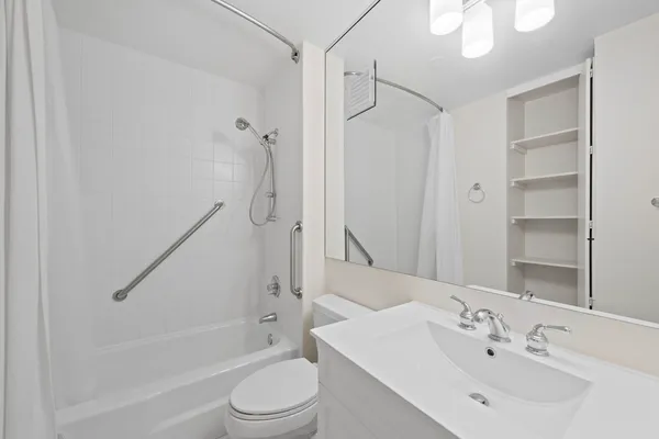 a bathroom with a bathtub shower sink vanity mirror and toilet
