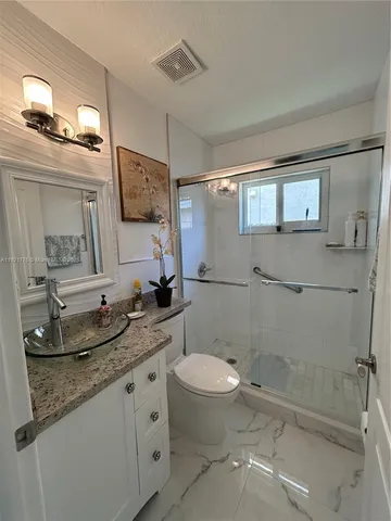a bathroom with a granite countertop sink mirror vanity and toilet
