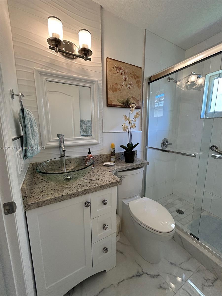 16620 Southwest 101st Terrace, Unit 1 Miami, FL 33196 - Photo 5 of 13 a bathroom with a granite countertop toilet sink and mirror