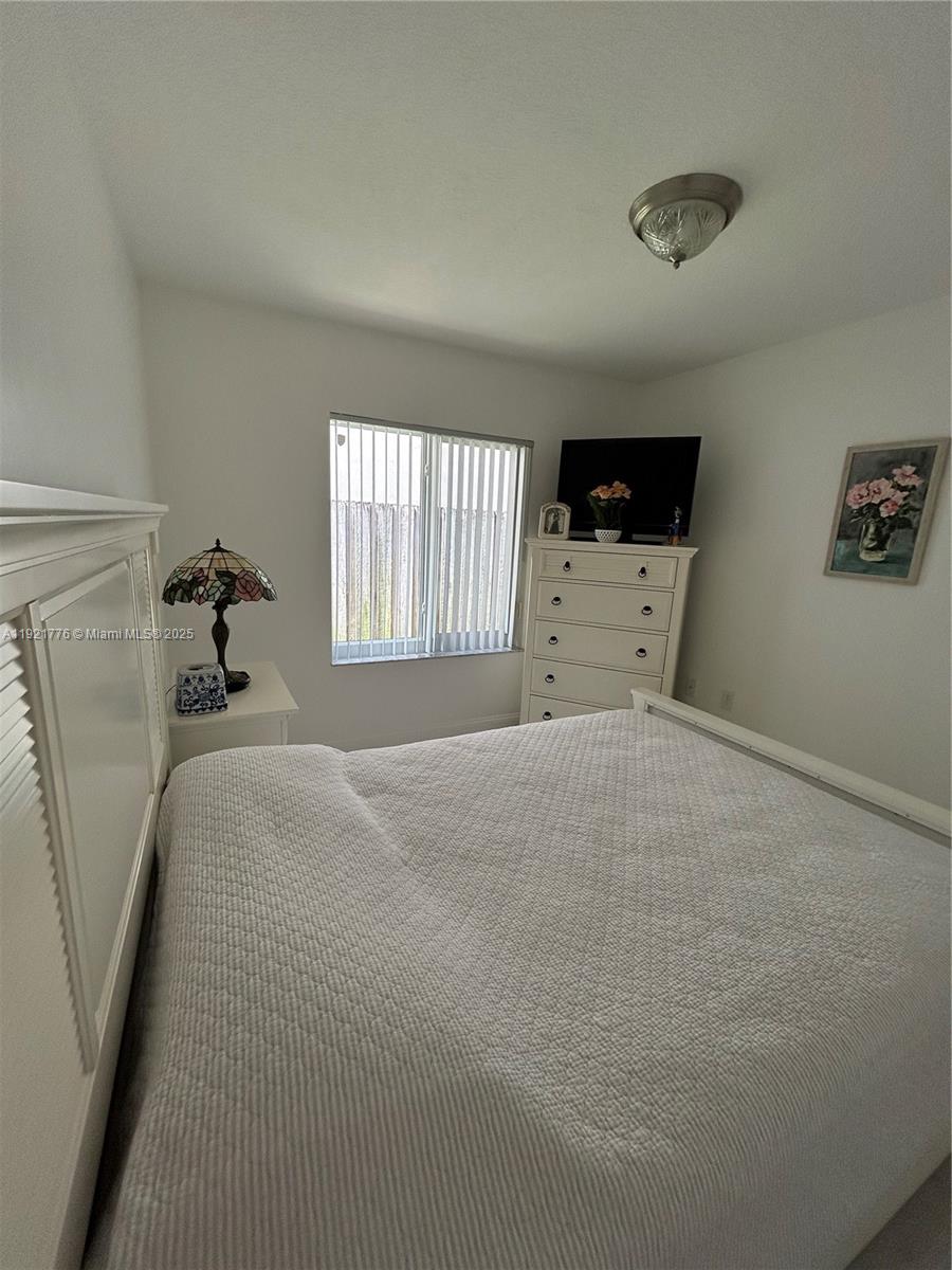 16620 Southwest 101st Terrace, Unit 1 Miami, FL 33196 - Photo 8 of 13 a bedroom with a bed and a large window