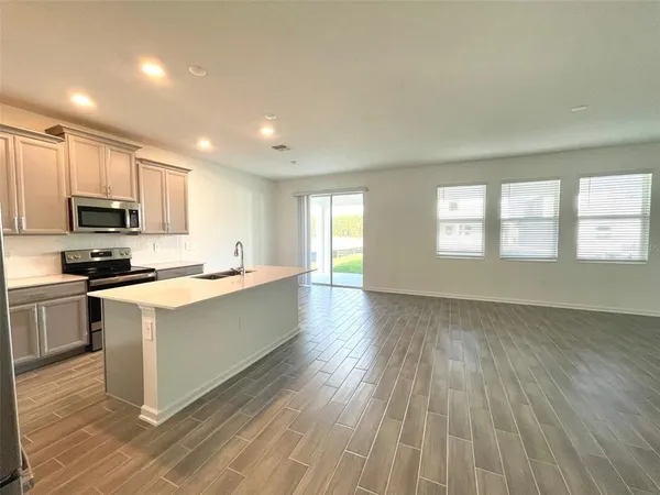 a large kitchen with cabinets wooden floor and stainless steel appliances