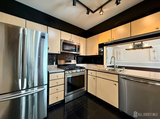 a kitchen with stainless steel appliances granite countertop a refrigerator a stove and a sink
