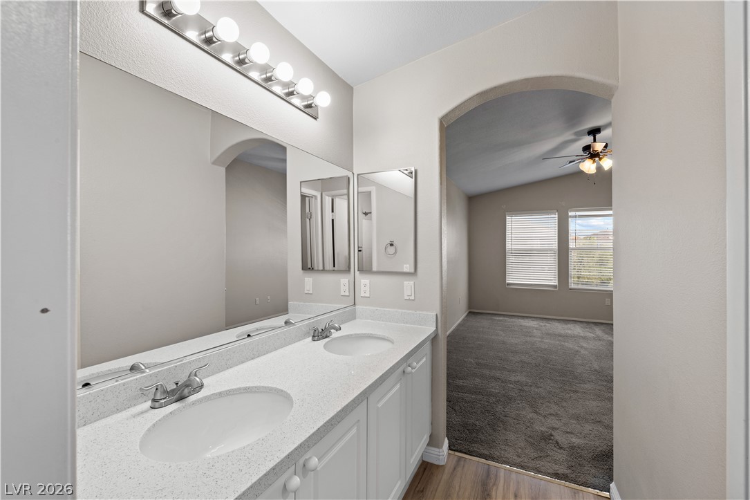 8777 Roping Rodeo Avenue, Unit 101 Las Vegas, NV 89178 - Photo 14 of 25 Double vanity with clean countertops in a well-appointed primary bathroom, with an adjoining primary bedroom.