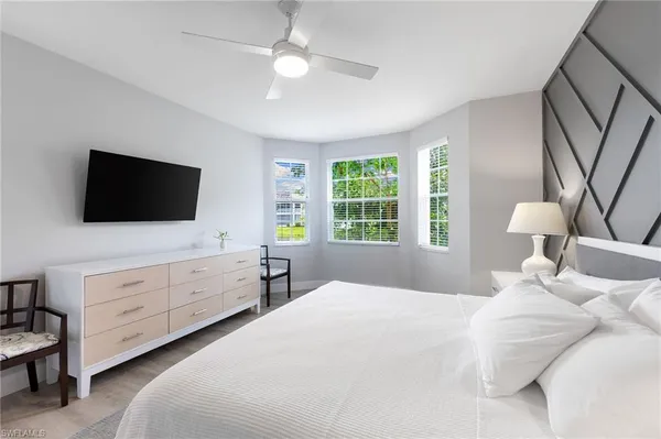 a bedroom with a large bed and a flat tv screen on dresser