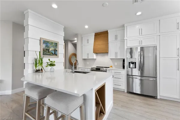 a kitchen with stainless steel appliances granite countertop a refrigerator a stove a sink a dining table and chairs