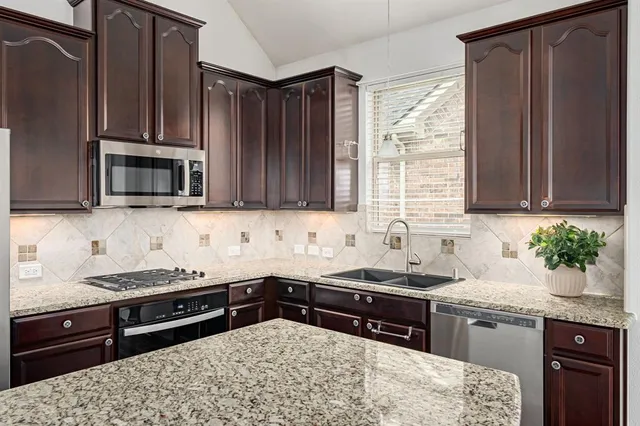 a kitchen with granite countertop a sink stainless steel appliances and cabinets