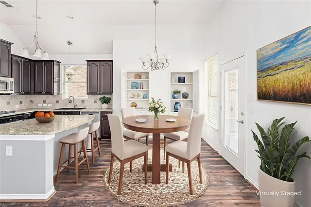 a kitchen with stainless steel appliances kitchen island granite countertop a table chairs and a refrigerator