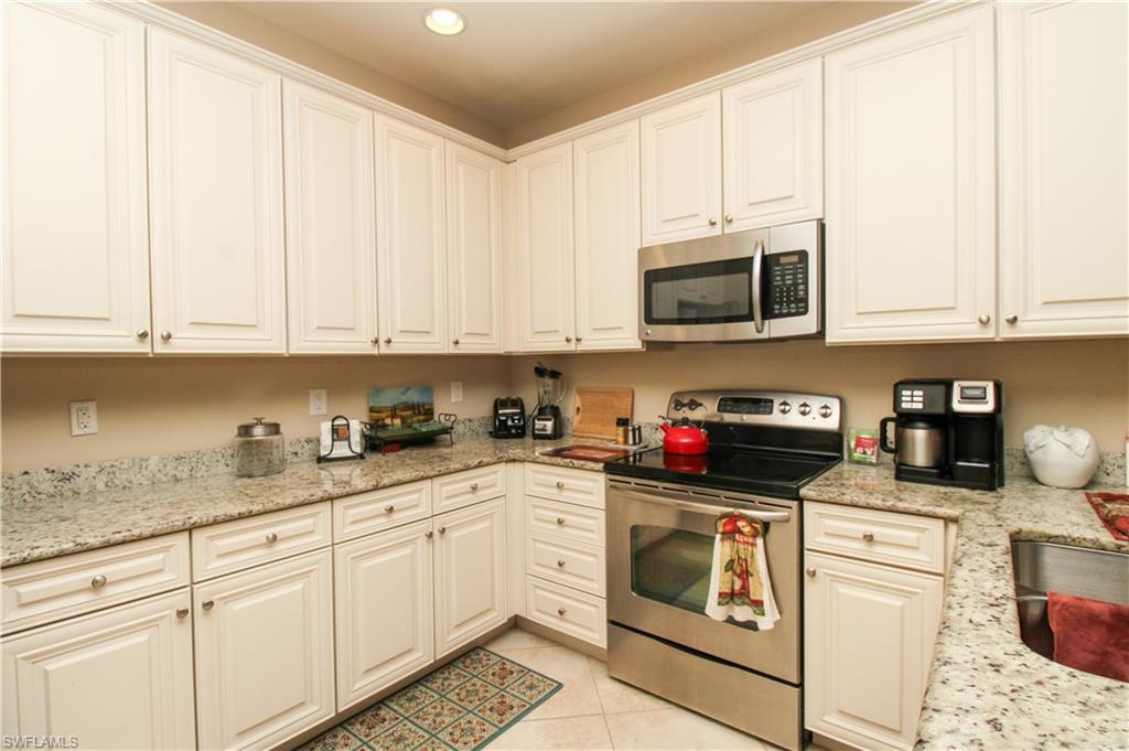 9054 Capistrano Street North, Unit 4003 Naples, FL 34113 - Photo 14 of 49 a kitchen with granite countertop white cabinets and stainless steel appliances