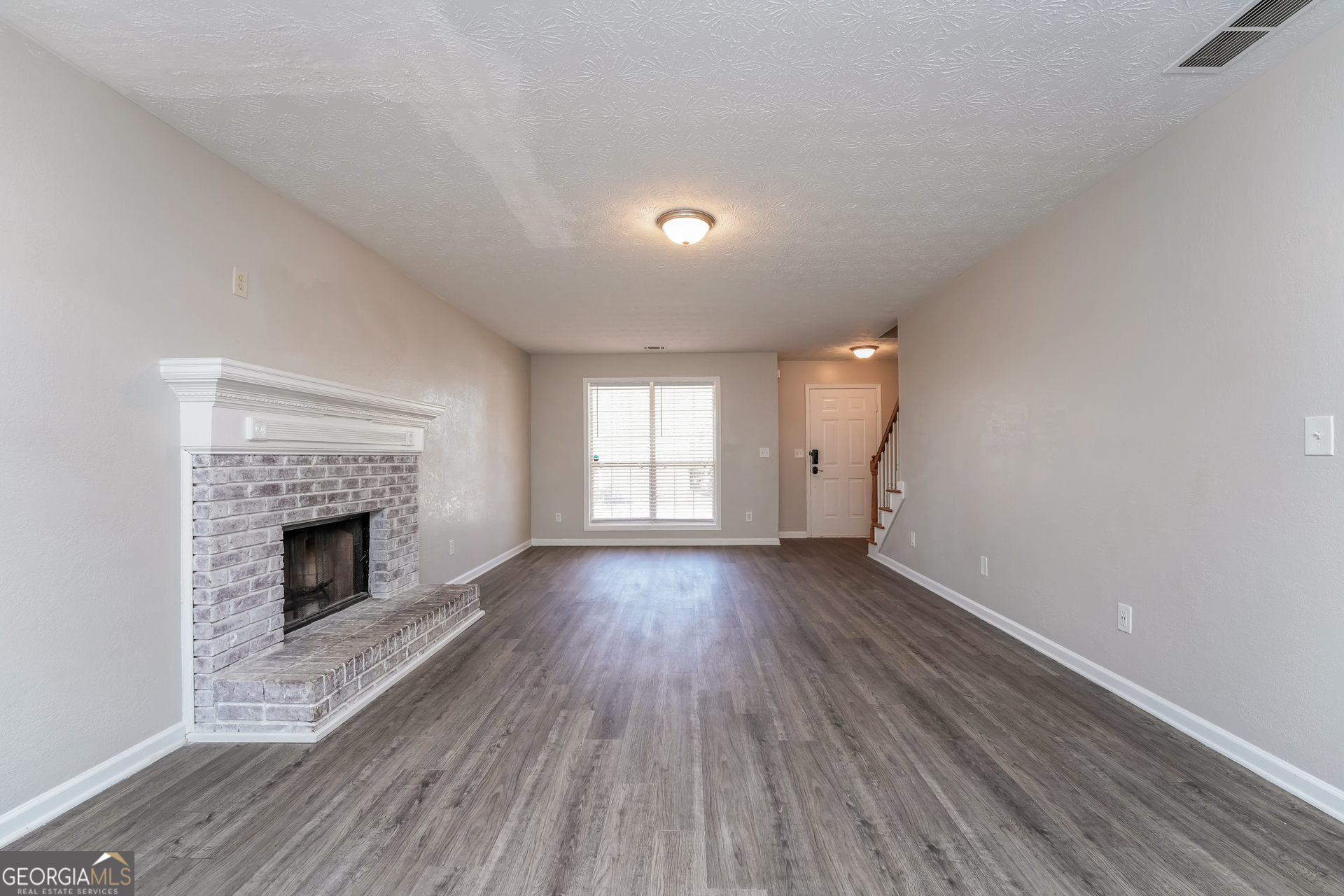 310 Alcovy Way Covington, GA 30014 - Photo 6 of 22 an empty room with wooden floor fireplace and windows