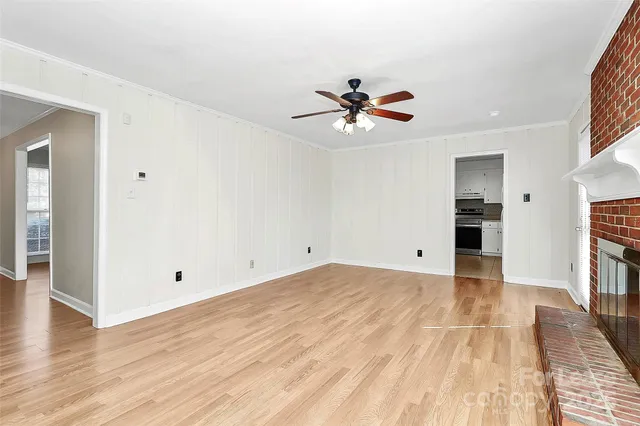 a view of empty room with wooden floor and ceiling fan