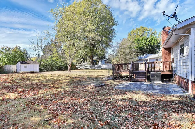 a view of backyard with large trees and wooden fence